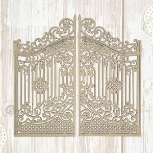 Puede incluir: Puerta de madera cortada con láser en dos partes, con intrincados adornos y barras verticales. La puerta presenta un diseño simétrico con adornos decorativos y un patrón detallado en la base. La madera es de color marrón claro natural.