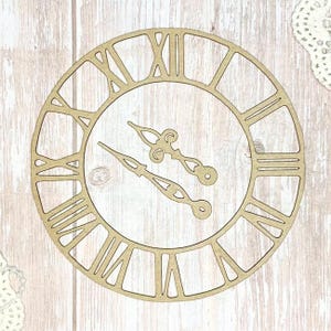 May include: A laser-cut wooden clock face with Roman numerals and decorative hands. The clock face is a light tan color, with a detailed open design. The hands are also light tan and have an ornate, vintage style.