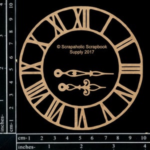 May include: A laser-cut wooden clock face with Roman numerals and two separate clock hands. The clock face is circular with the text "Scrapaholic Scrapbook Supply 2017". The clock face measures approximately 4 inches in diameter.