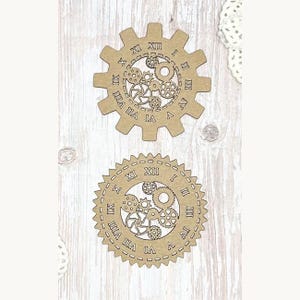 May include: Two wooden gear-shaped cutouts with Roman numerals and internal gear designs. The top gear has a cogwheel shape, while the bottom one is circular with a dotted border. Both are light brown.