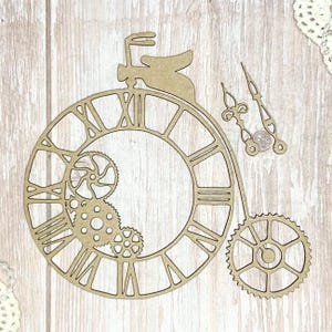 May include: A laser-cut wooden clock face with Roman numerals, gears, and clock hands. The clock design includes a rabbit silhouette and a large gear. The clock face is made of light brown wood and is set against a light wood background.
