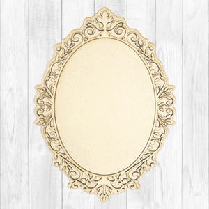 May include: An oval-shaped wooden plaque featuring an intricate, laser-cut filigree border with scrolling leaf and vine patterns. The center of the plaque is a smooth, solid, light beige oval surface, framed by the detailed, cut-out decorative edge.