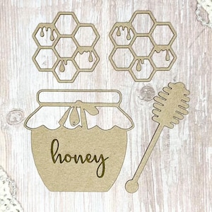 May include: Wooden cutouts of honey-themed items. Includes two honeycomb shapes with dripping honey, a jar labeled "honey", and a honey dipper. The items are made of light brown wood.