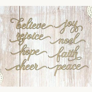 Op de afbeelding: Houten uitsparingen met de woorden "Believe", "Joy", "Rejoice", "Noel", "Hope", "Faith", "Cheer" en "Peace" in een cursief lettertype. De woorden zijn lichtbruin en gerangschikt in twee kolommen. De achtergrond is een lichte houtnerf.