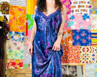 Pode incluir: Um vestido de cetim roxo com estampa floral e acabamento em renda. O vestido é usado com botas de combate pretas.