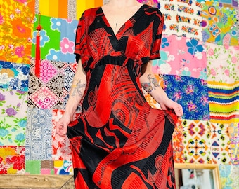 Könnte beinhalten: Ein langes rotes und schwarzes Maxikleid mit geometrischem Muster. Das Kleid hat einen V-Ausschnitt und kurze Ärmel.