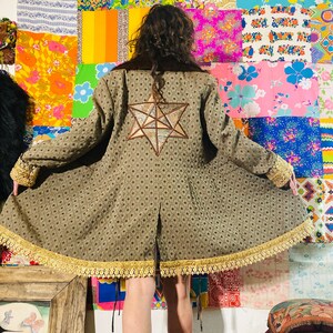 May include: A long-sleeved brown coat with a gold lace trim and a large, star-shaped patch on the back. The star is made of a patchwork of different fabrics and colours.