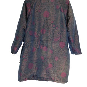 May include: A long-sleeved, paisley patterned jacket with a dark green and burgundy color scheme. The jacket has a high collar and a button closure.