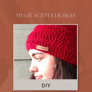 Puede incluir: Un gorro de ganchillo de color rojo vibrante con una pequeña etiqueta rectangular de color beige similar al cuero en el lateral. El texto MYGRACEFULDESIGN aparece sobre la imagen y la palabra DIY está impresa en negro debajo del gorro.