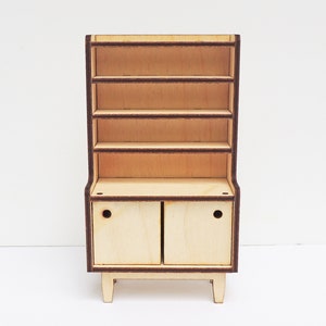 May include: A wooden hutch with a cabinet and open shelves. The hutch is made of light wood with dark brown trim. The cabinet has two doors with a small round cutout on each door.