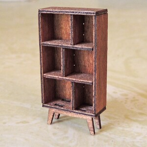 May include: A small wooden bookshelf with six shelves and four legs. The bookshelf is made of dark brown wood and has a rustic look.
