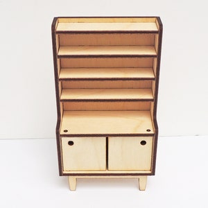 May include: A wooden hutch with a top shelf unit and a lower cabinet with two doors. The hutch is made of light wood with a brown trim. The doors have a simple design with a small hole in each door.