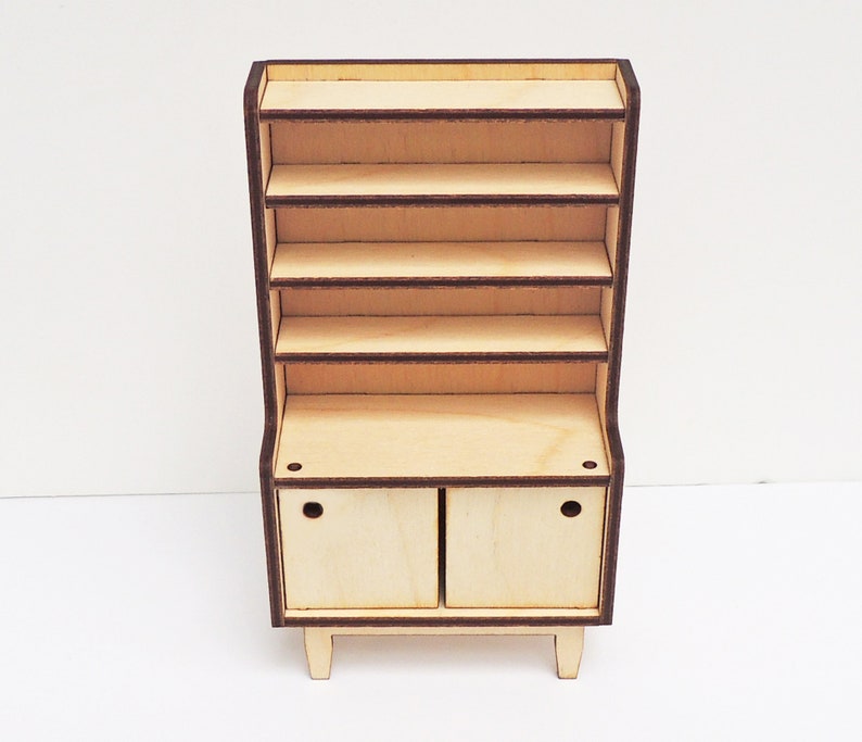 May include: A wooden hutch with a top shelf unit and a lower cabinet with two doors. The hutch is made of light wood with a brown trim. The doors have a simple design with a small hole in each door.