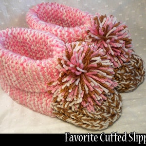 May include: Pink and brown knitted slippers with a fluffy pom-pom on each toe. The slippers have a white and pink striped pattern and a brown and white striped cuff.