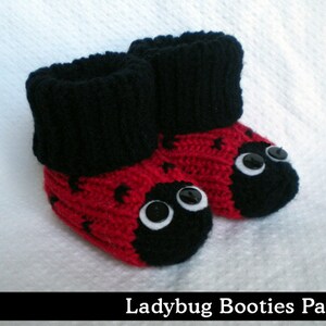 May include: Red and black knitted baby booties with black button eyes, resembling a ladybug.
