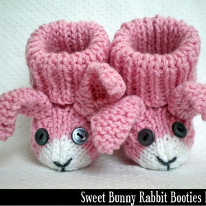 May include: Pink knitted baby booties shaped like bunnies with white faces and black button eyes.  The booties have a fold-over cuff and are made with a soft yarn.