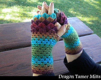 May include: A pair of colourful fingerless gloves with a dragon scale pattern. The gloves are crocheted in shades of brown, green, blue, and red. The gloves are called "Dragon Tamer Mitts".