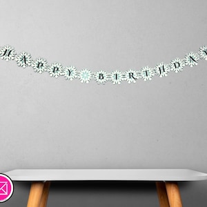 以下が含まれることがあります： 「HAPPY BIRTHDAY」の文字が黒字で書かれた白いバナー。文字は、白と水色の雪の結晶型の切り抜きで繋がれています。バナーは灰色の壁に掛けられています。