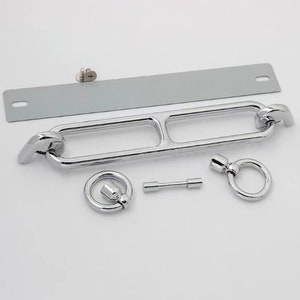 May include: A silver metal hardware set for a door or cabinet. The set includes a long, curved handle with two rings, a smaller ring, a metal plate, and a small pin.