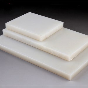 May include: Three white plastic sheets stacked on top of each other. The sheets are smooth and have a slight sheen.
