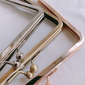 Puede incluir: Tres marcos de bolso de metal en diferentes acabados: plata, oro y oro rosa. Cada marco tiene dos cierres redondos de metal.