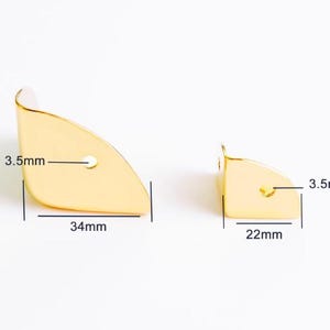 May include: Two gold-colored metal corner brackets. The larger bracket is 34mm long and 3.5mm wide, with a small hole. The smaller bracket is 22mm long and 3.5mm wide, also with a small hole. Both are on a white background.