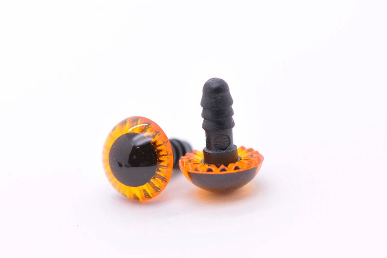 May include: Two orange plastic safety eyes with black pupils and a black plastic washer. The eyes have a textured, wavy rim.