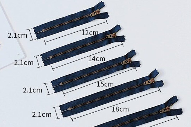 K&ouml;nnte beinhalten: F&uuml;nf marineblaue Rei&szlig;verschl&uuml;sse mit Messing-Zippern, die in der Gr&ouml;&szlig;e von 12 bis 18 Zoll reichen. Jeder Rei&szlig;verschluss wird in Zoll gemessen und mit der entsprechenden L&auml;nge beschriftet.