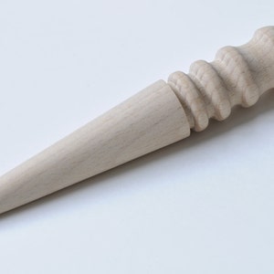 May include: A wooden leather stitching tool with a tapered point and a rounded, textured handle.