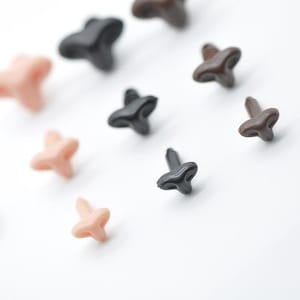 May include: A selection of small, star-shaped items in shades of brown, black, and peach. These objects are arranged on a white surface. The shapes have a textured appearance. The image presents a visually appealing arrangement.