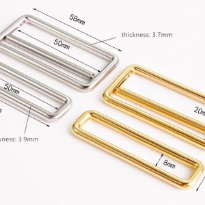 May include: Metal rectangular slider buckles in silver and gold. The silver buckles measure 58mm x 50mm with a thickness of 3.9mm and 3.7mm. The gold buckles measure 58mm x 27mm, 20mm x 16mm, and 8mm.