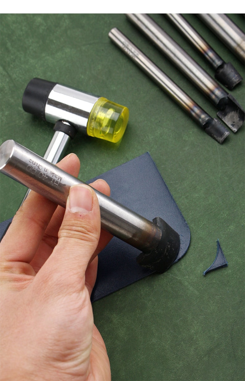 May include: A hand holds a metal leather punch tool with a black handle. The tool is being used to punch a hole in a piece of blue leather. A yellow rubber mallet is also visible in the image. The tool is labeled "TY 40  MADE IN CHINA".