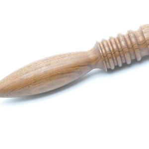 May include: A wooden massage tool with a rounded, textured head and a long, tapered handle.