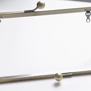 May include: An antique brass purse frame, rectangular in shape, with a ball clasp and two decorative ball accents. The frame has a hinged opening and small loops for attaching fabric. Ideal for crafting projects.