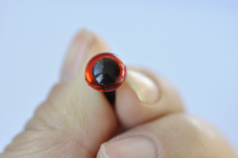 Puede incluir: Un solo ojo de seguridad de pl&aacute;stico rojo con pupila negra, utilizado para manualidades y la fabricaci&oacute;n de mu&ntilde;ecas.