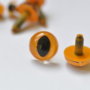 May include: Two orange plastic safety eyes with black pupils and a metal shank. The eyes are for craft projects.