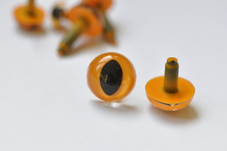 May include: Two orange plastic safety eyes with black pupils and a metal shank. The eyes are for craft projects.