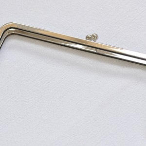 May include: Silver-toned metal purse frame with two small round decorative accents on the top.