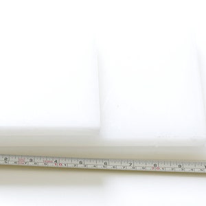 May include: Two white rectangular pieces of foam stacked on top of each other, measured with a ruler in inches.