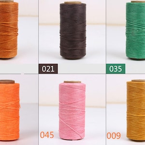 May include: Six spools of waxed thread in various colors, including orange, brown, green, pink, and yellow. The spools are labeled with numbers.