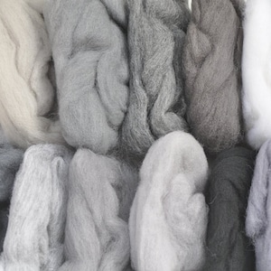 May include: A collection of various shades of gray wool roving, including white and black, arranged in a semi-circle.