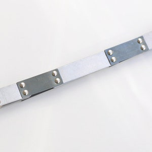 May include: A silver and black metal belt with silver studs and a gold buckle.