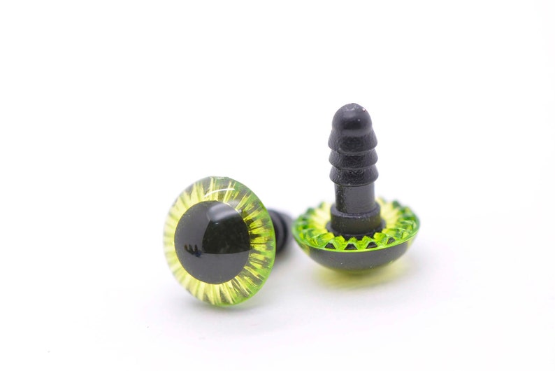May include: Two green and yellow plastic safety eyes with black pupils and a black plastic back for attaching to a stuffed animal or craft project.