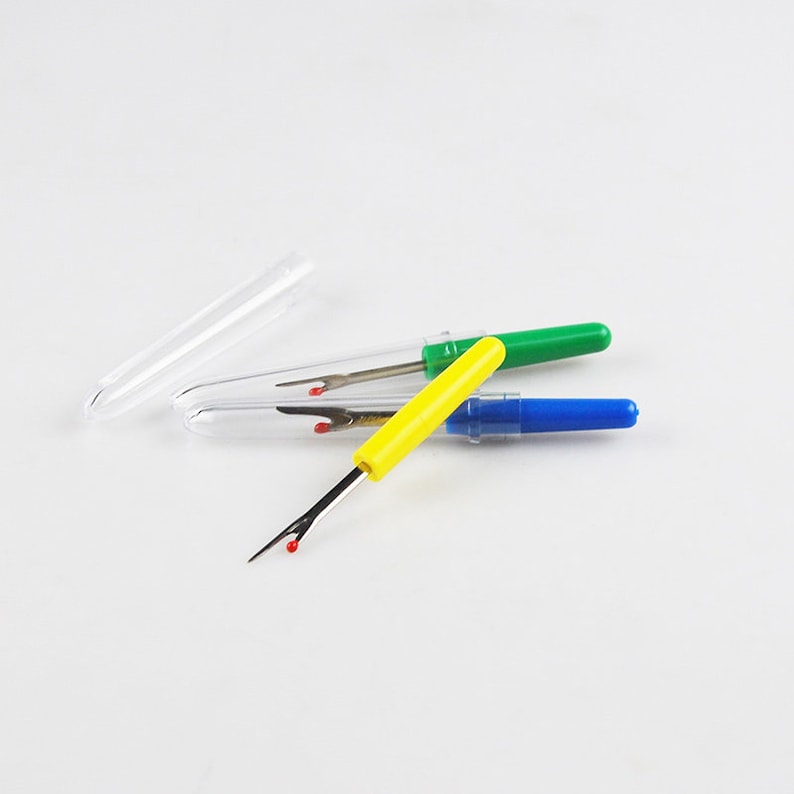 May include: Three thread snips with clear plastic cases. The snips have yellow, green, and blue handles.