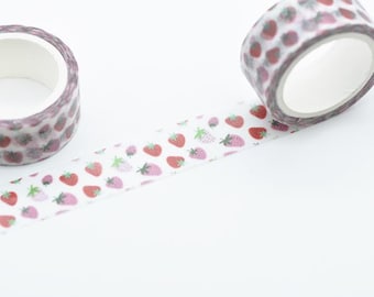 May include: Two rolls of decorative washi tape with a strawberry pattern. The tape features red, pink, and green strawberries on a white background. One roll is unrolled, showing the pattern. The rolls are on a white surface.