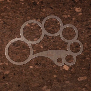 May include: A metal tool with a series of circular cutouts of different sizes, labeled with their diameters in millimeters. The tool is designed for measuring the diameter of objects.