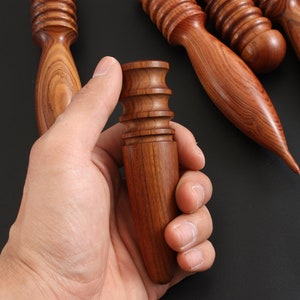 May include: A set of five wooden tools for leather crafting. The tools are made of reddish-brown wood and have different shapes and sizes. The tools are used for smoothing, shaping, and finishing leather.