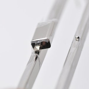 Könnte beinhalten: Nahaufnahme eines silbernen Metallscharniers mit einer kleinen silbernen Kugel oben.