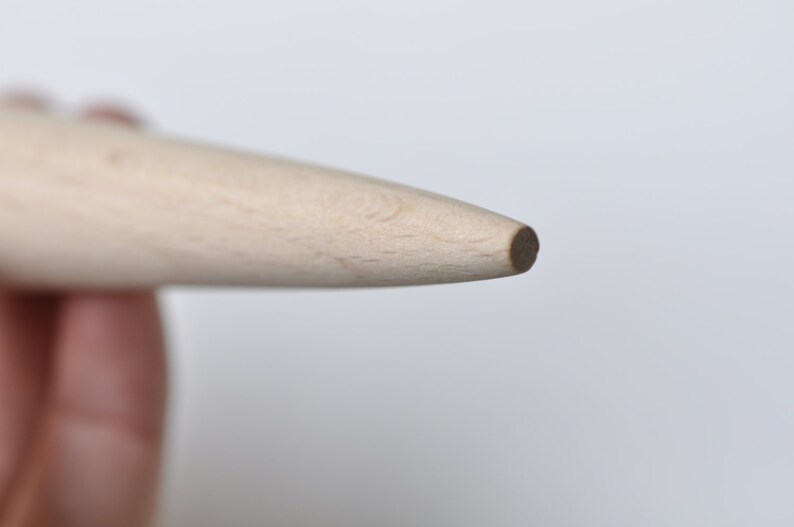 May include: Close-up of the tip of a wooden rolling pin. The tip is rounded and smooth.