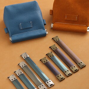 May include: Five metal bag strap buckles with a brass finish and a blue leather bag and a brown leather bag.